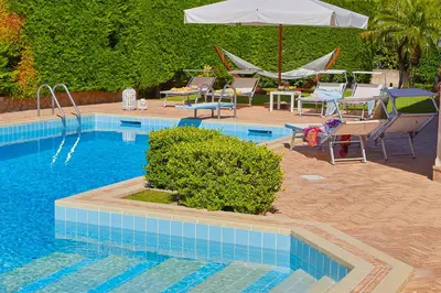 a swimming pool with chairs and an umbrella at Villa Cottone - 5 suite con piscina privata - tra Palermo e Cefalù in Altavilla Milicia