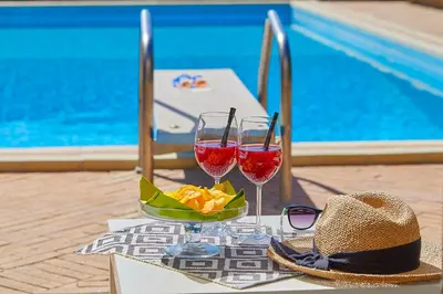 a table with two glasses of wine and a hat at Villa Cottone - 5 suite con piscina privata - tra Palermo e Cefalù in Altavilla Milicia