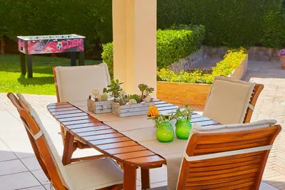 a wooden table with chairs and plants on a patio at Villa Cottone - 5 suite con piscina privata - tra Palermo e Cefalù in Altavilla Milicia