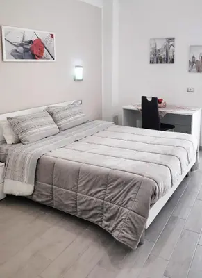 a white bedroom with a large bed and a desk at Tourist House Palermo in Palermo