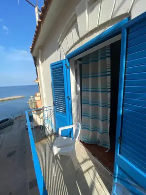 a balcony with a blue door and a white chair at Casa Vacanze Marco Polo vista mare in Trappeto