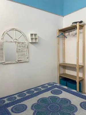 a bedroom with a bed with a blue rug and a shelf at Casa Vacanze Marco Polo vista mare in Trappeto
