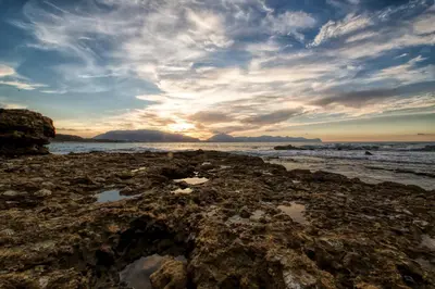 a sunset on the beach with rocks at Baia Marina Suite with private jacuzzi in Balestrate