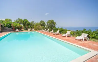 a large swimming pool with lounge chairs and the ocean at Nice Apartment In Collesano Pa in Lascari