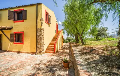 a house with red windows and stairs next to a tree at Stunning Apartment In Collesano Pa in Lascari