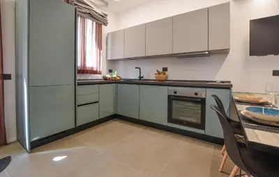 a kitchen with white cabinets and a table with chairs at Stunning Apartment In Trappeto With Wifi in Trappeto