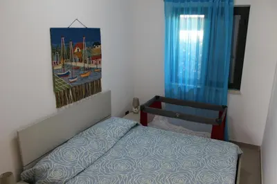 a small bedroom with a bed and a painting on the wall at Cento Pini Holiday Cefalù in Buonfornello
