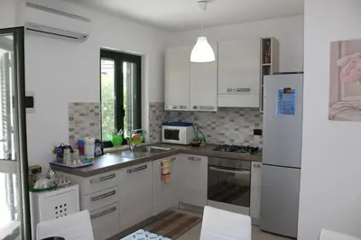 a kitchen with white cabinets and a white refrigerator at Cento Pini Holiday Cefalù in Buonfornello