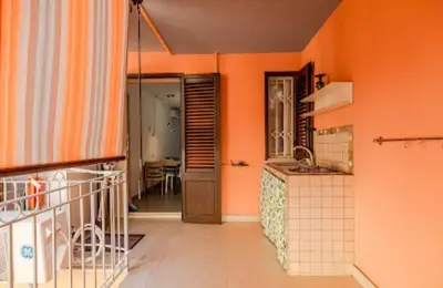 a kitchen with orange walls and a hallway with a sink at Paradiso del mare, Appartamento accogliente vicino a mare, metro, aeroporto e Palermo in Capaci