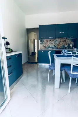 a kitchen with blue cabinets and a white table and chairs at DV holiday home in Isola delle Femmine