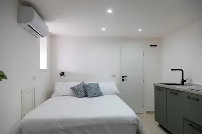 a white bedroom with a bed and a kitchen at Stratuzza Apartments in Palermo
