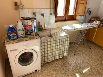 a laundry room with a washing machine and a table at La Dimora della Maestra in Vita