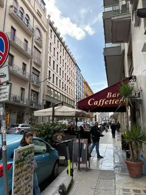 a blue car parked on a city street with a cafe at Residenza Stabile 64 in Palermo
