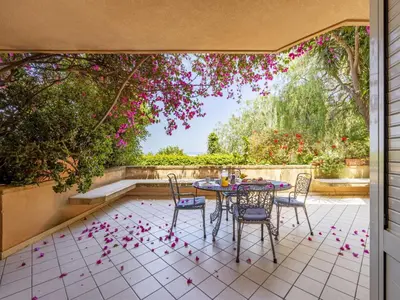 a table and chairs on a patio with pink flowers at Apartment Cicladi Anafi by Interhome in Santa Flavia