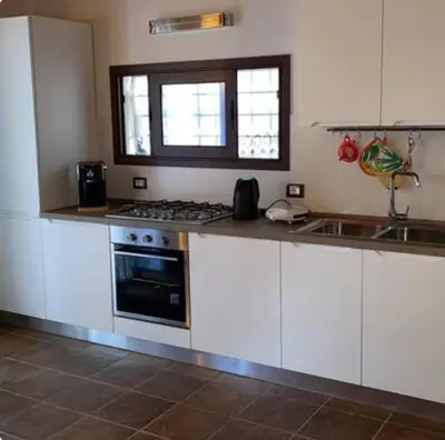 a kitchen with white cabinets and a stove top oven at Lally in the Sky moderno monovano panoramico ed accessoriato in Scopello