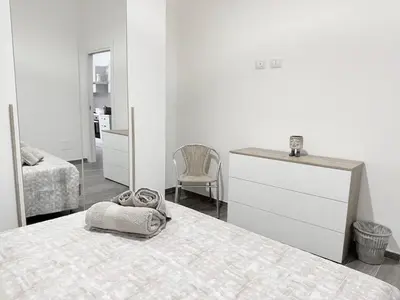 a white bedroom with a bed and a dresser at Casa Francesca in Capaci