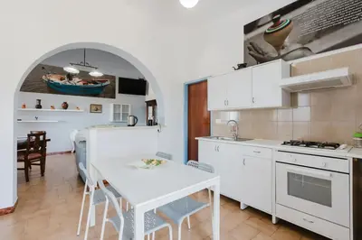 a kitchen with white cabinets and a white table at Archi in Balestrate
