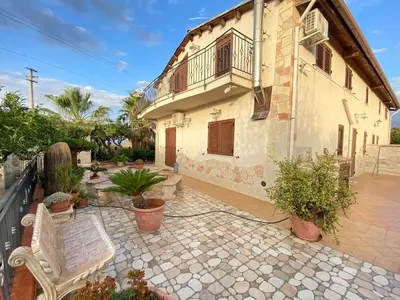 a house with a balcony and a patio with plants at Villa Sunset in Campofelice di Roccella