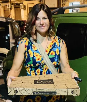 a woman holding a pizza box in front of a truck at irenes holiday house in Palermo