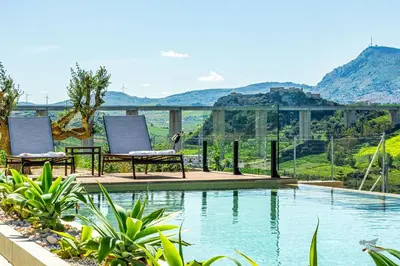 a pool with two chairs and a view of mountains at Villa Castello in Balestrate