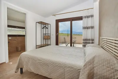 a bedroom with a large bed and a balcony at Villa Al-Kurum in Alcamo Marina