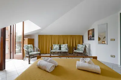 a bedroom with a bed and a rattan chair at Villa Tocco vicino al mare in Balestrate