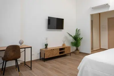 a bedroom with a desk and a tv on a wall at Marina Rooms - Guesthouse in Palermo