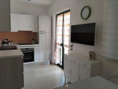 a kitchen with white cabinets and a clock on the wall at Villetta al villaggio 101 pini in Campofelice di Roccella
