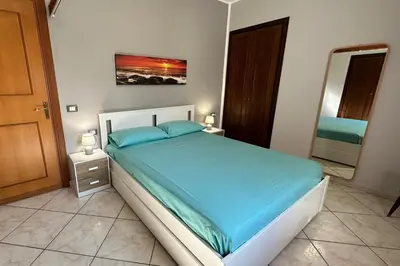 a bedroom with a bed with blue sheets and a mirror at Casa Punta Barcarello, Sferracavallo fronte mare e tramonti da sogno, a due passi dalla splendida spiaggia di Mondello in Palermo