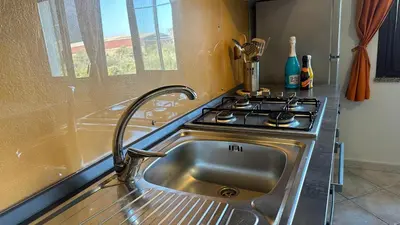 a kitchen with a stainless steel sink and a stove at Casa Punta Barcarello, Sferracavallo fronte mare e tramonti da sogno, a due passi dalla splendida spiaggia di Mondello in Palermo
