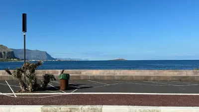 a parking lot next to the water with a parking meter at Casa Punta Barcarello, Sferracavallo fronte mare e tramonti da sogno, a due passi dalla splendida spiaggia di Mondello in Palermo
