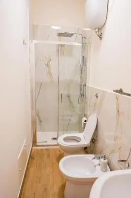 a bathroom with a toilet and a shower and a sink at Tribunale Suite in Termini Imerese