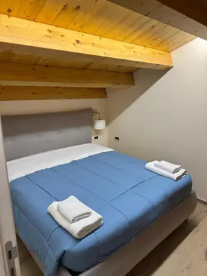 a bedroom with a blue bed with wooden ceilings at Tribunale Suite in Termini Imerese