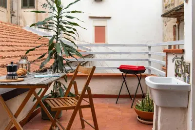 a table and chairs on a balcony with a plant at Civico 61 in Palermo