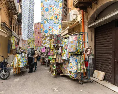a group of people walking down a street in a market at Civico 61 in Palermo