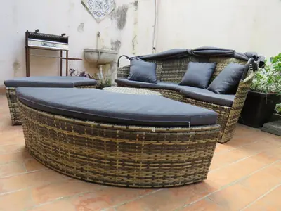 a large wicker chair and couch sitting on a patio at Loft with terrace in the city centre in Palermo