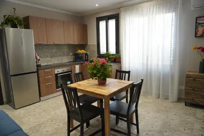 a kitchen with a wooden table with chairs and a refrigerator at Maria's Home in Altavilla Milicia
