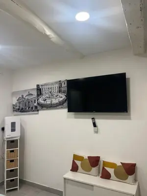 a flat screen tv on a white wall with two chairs at All'Oro Suite & go in Palermo