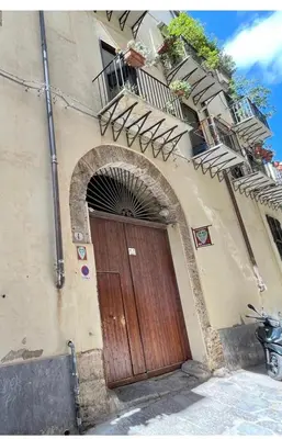 a building with a wooden door and a balcony at All'Oro Suite & go in Palermo