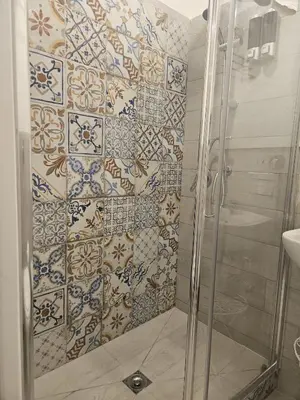 a shower with blue and white tiles on the wall at All'Oro Suite & go in Palermo