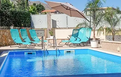 a swimming pool with blue chairs and an umbrella at Stunning Home In Trabia in Trabia