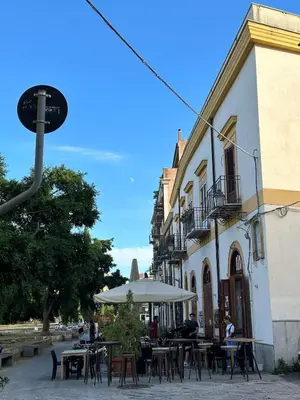an outdoor cafe with tables and umbrellas in front of a building at Rosalia Holiday Home in Palermo