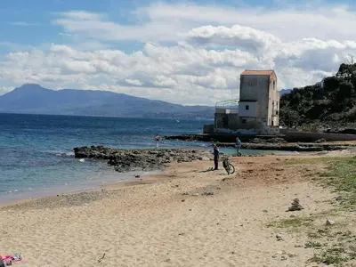 a person standing on a beach near the water at Terrazza al mare in Santa Flavia