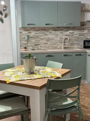 a kitchen with a wooden table with green chairs at A Casa di Frank in Palermo