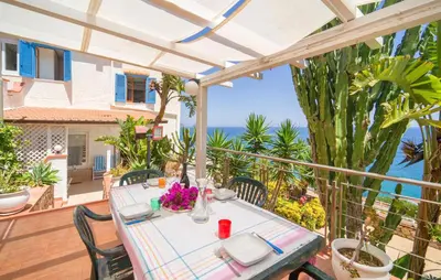 a table on a balcony with a view of the ocean at Nice Home In Altavilla Milicia in Altavilla Milicia