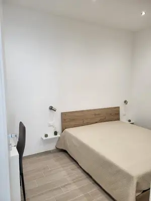 a white bedroom with a bed and a chair at Sguardo a Ponente in Castellammare del Golfo