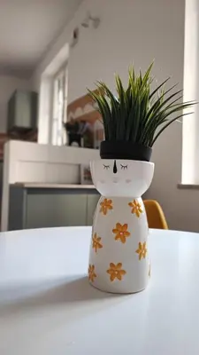 a white vase with a plant in it on a table at Casa GADA in Palermo
