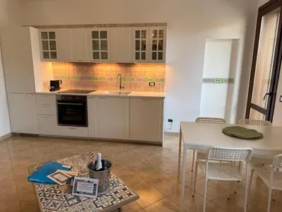 a kitchen with white cabinets and a table with chairs at Carol's Sicily Dream in San Vito lo Capo