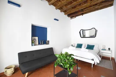 a bedroom with a bed and a couch and a mirror at iFlat Casa Riccino in Palermo