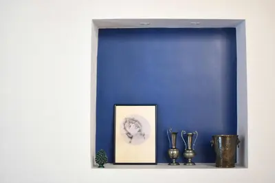 a blue wall with a picture and vases on a shelf at iFlat Casa Riccino in Palermo